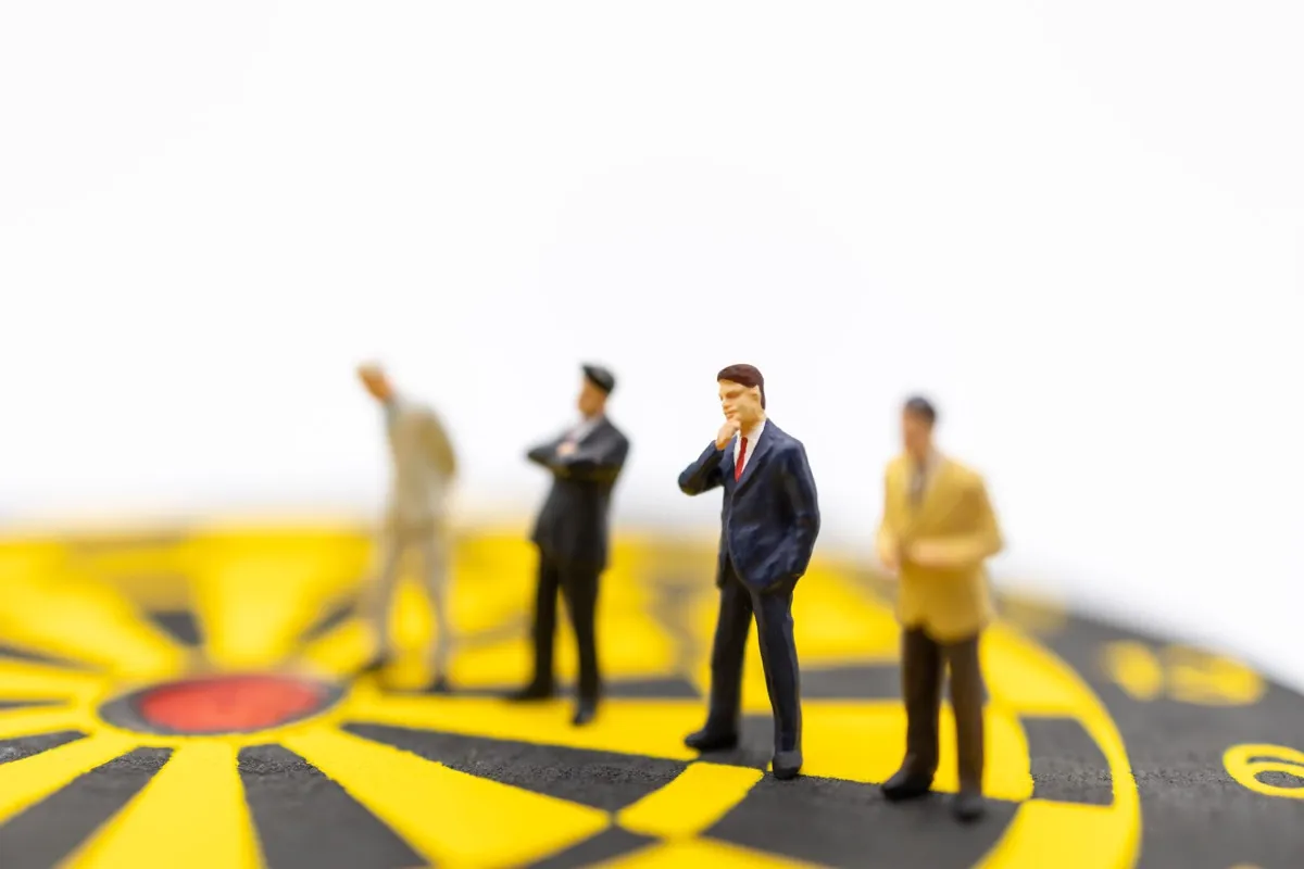 Miniature figures standing on a dartboard's centre, the question of who actually holds control