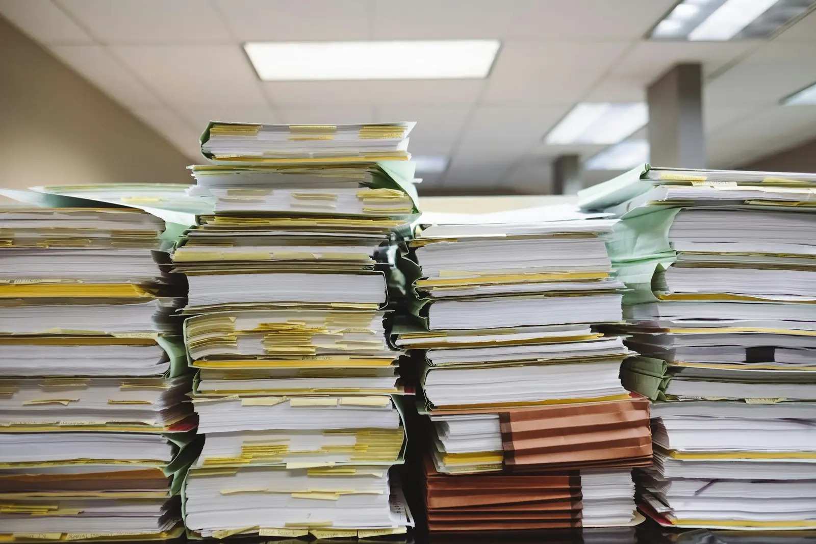 Stacked paper files in an office, the documents a DIFC application has to assemble