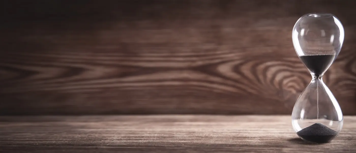 An hourglass on a dark wooden desk, the time a DIFC formation actually takes stage by stage