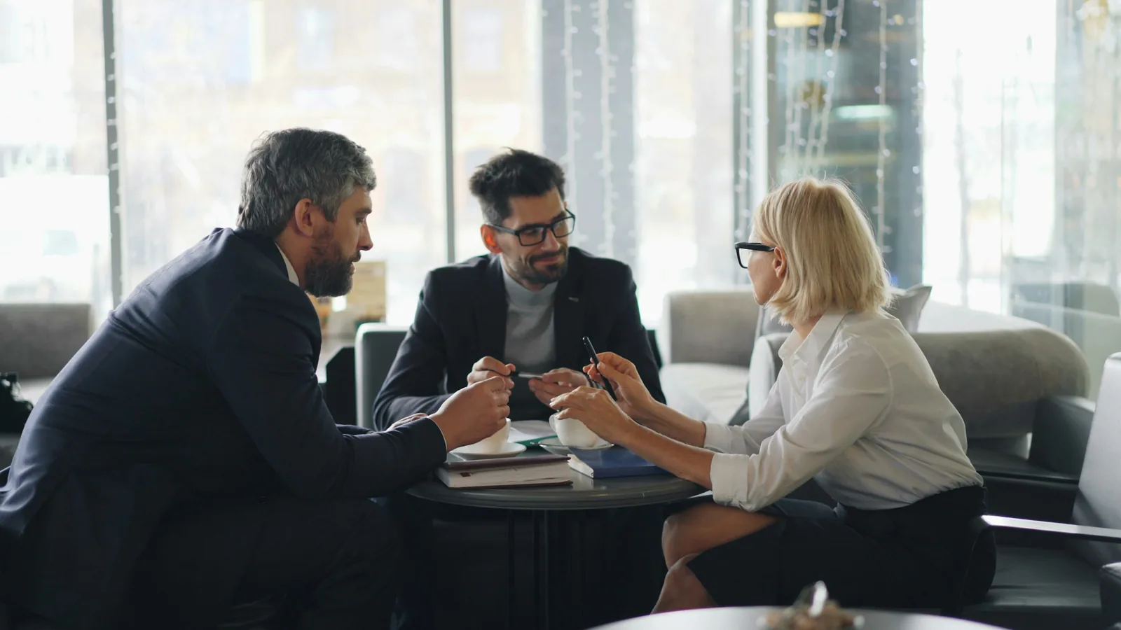 Three advisers in conversation in a modern office, the team a family office arrangement needs around it