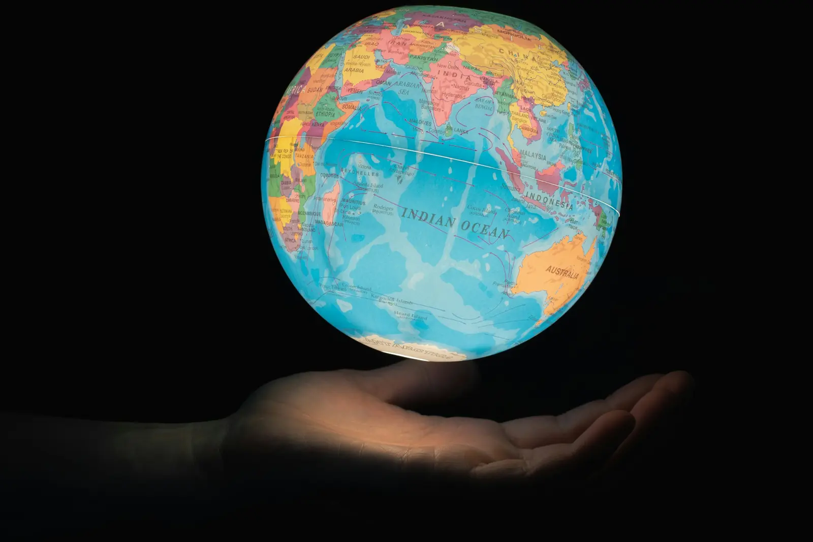 A globe held in an open hand, the international assets a Prescribed Company can hold