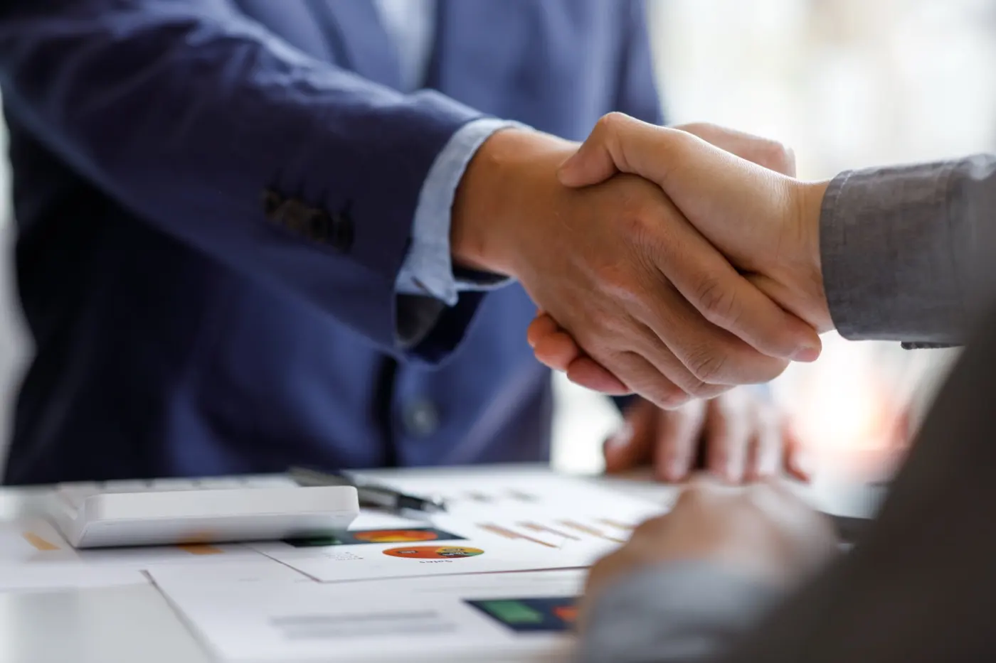 A handshake closing a deal over signed terms, the moment a co-investment structure has to already exist